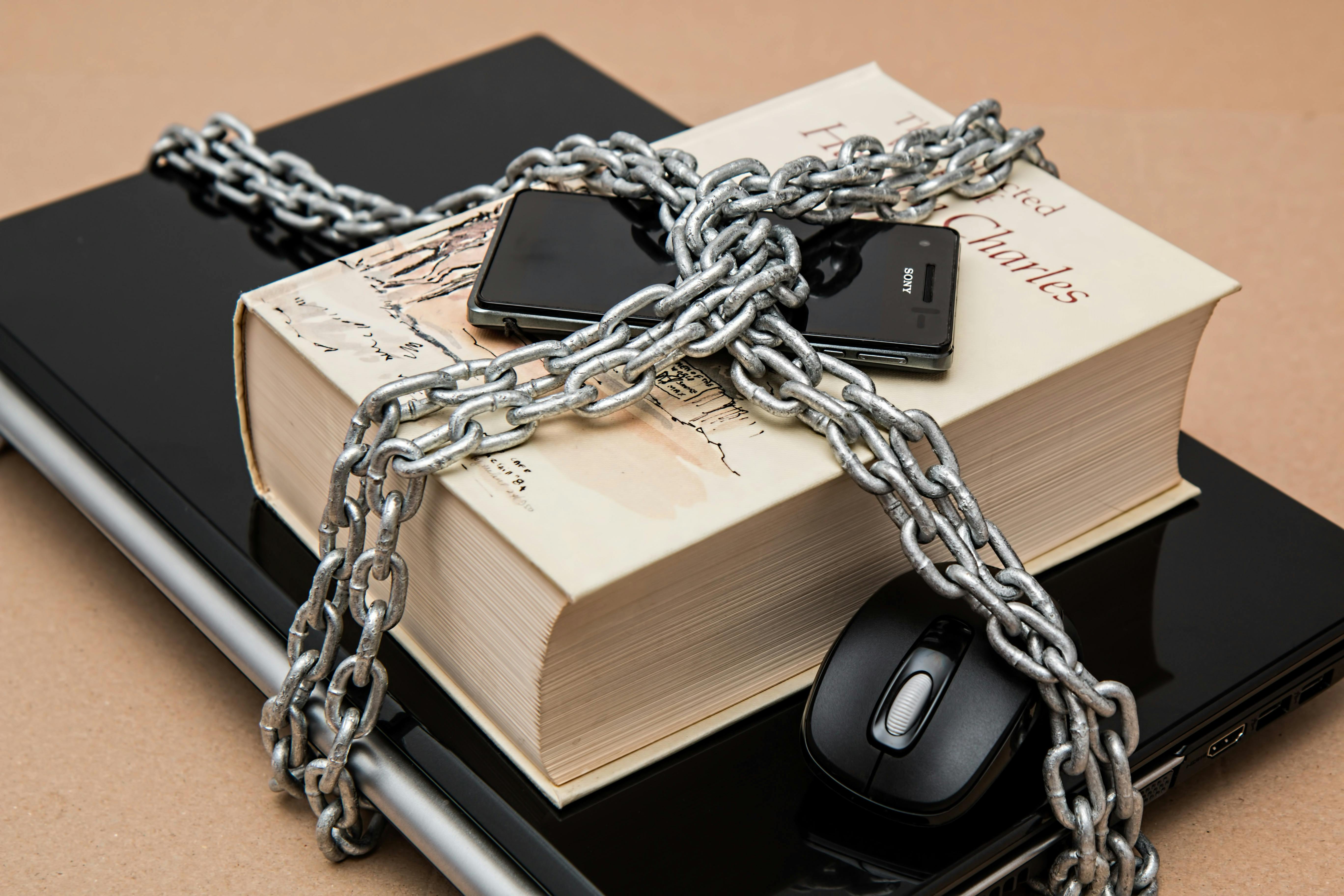 A phone, book, laptop and mouse locked up with a chain