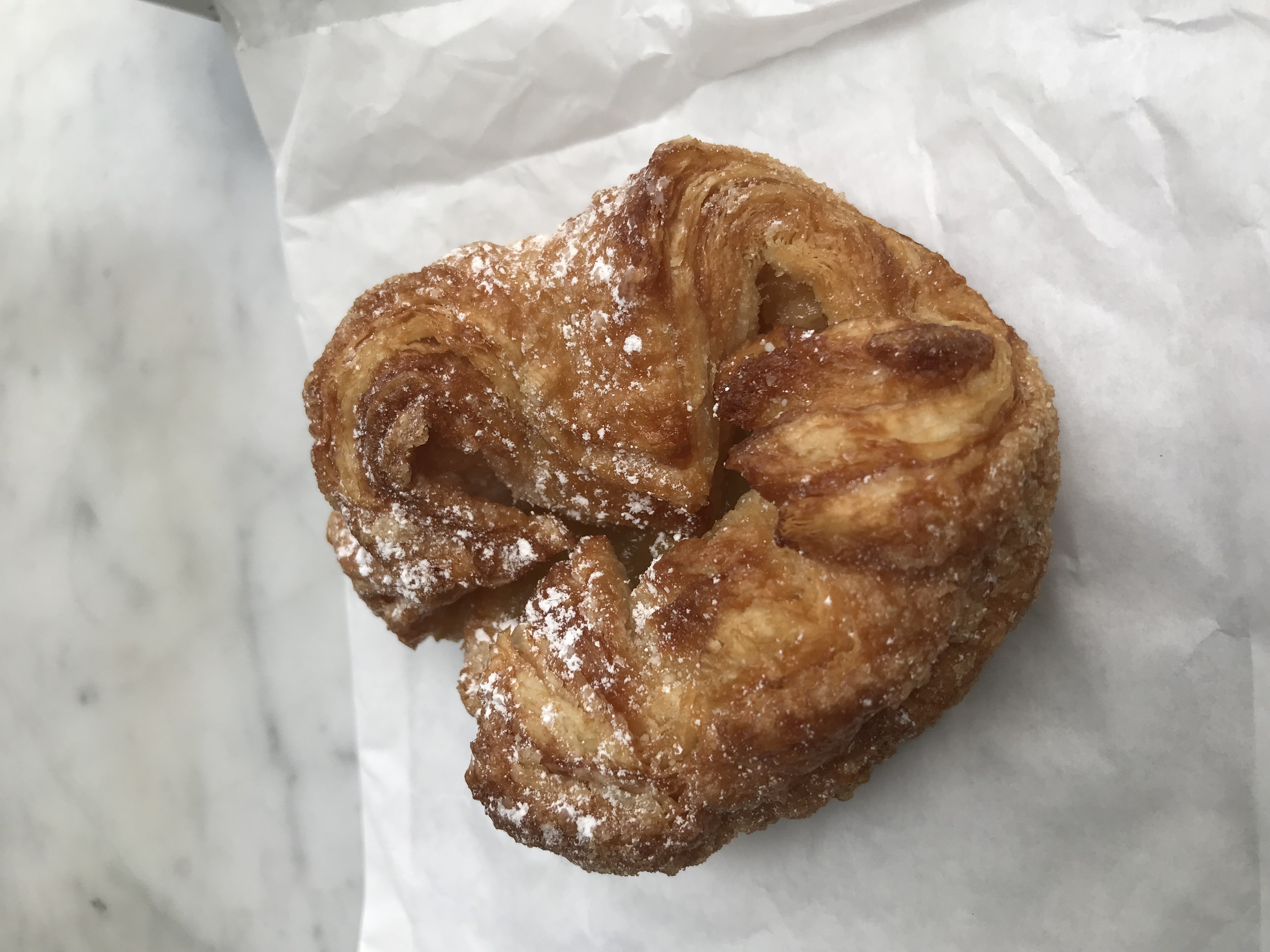 Individual golden kouign-amann pastry dusted with sugar