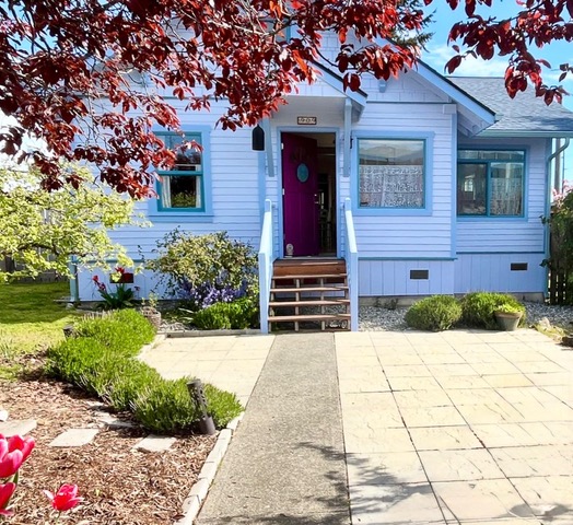 Cottage painted blue and white with a garden and paving at the front.
