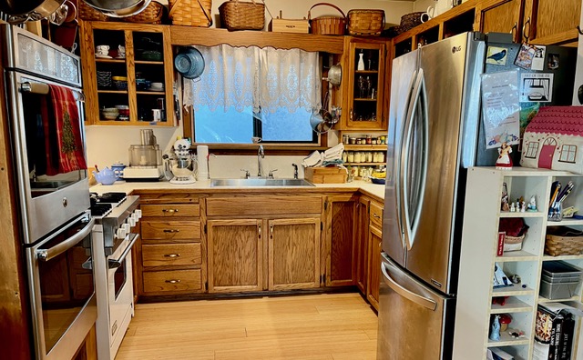 Kitchen with large ovens and large fridge,, wooden cupboards and drawers.