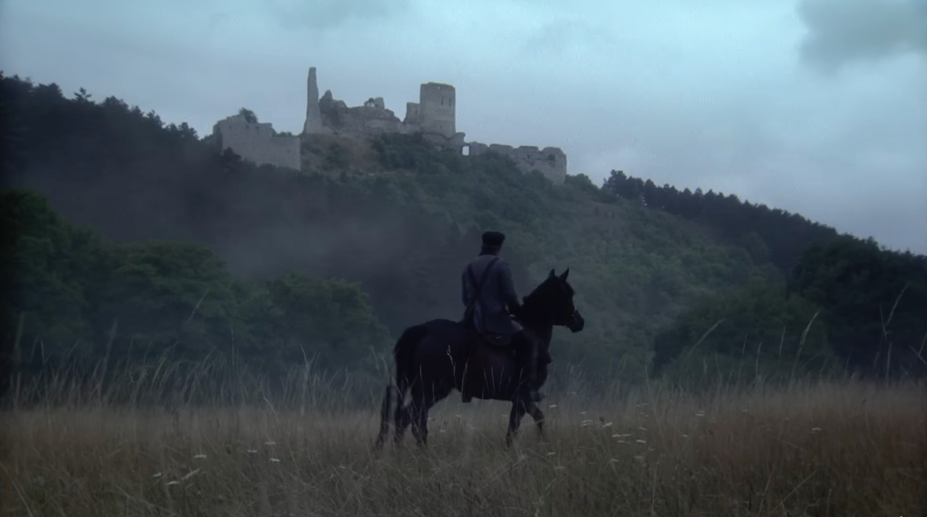 A screenshot showing Victor on horseback passing through a grassy plain. A ruined castle is visibile in the distance.
