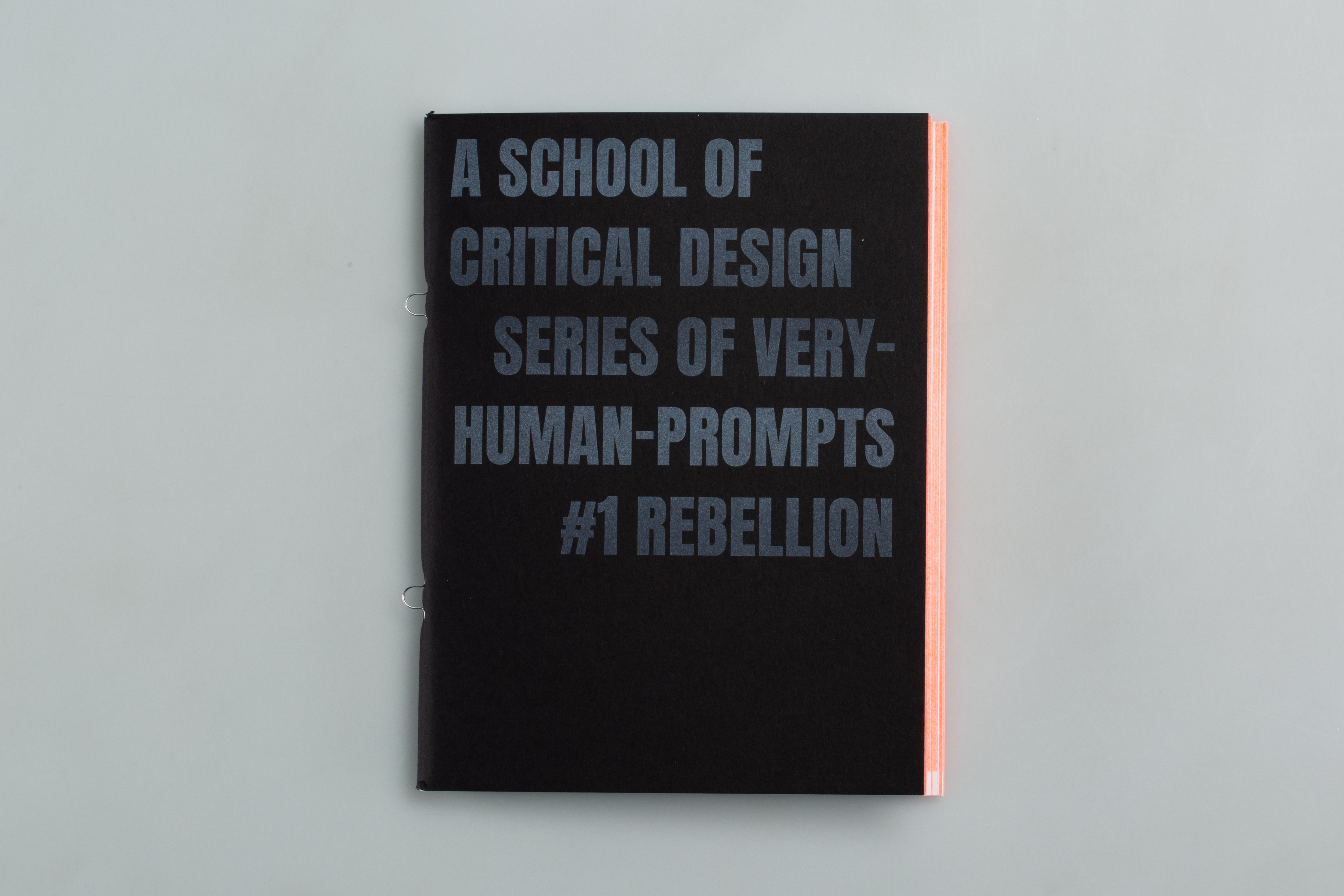 A black front cover with printed white letters reading "A School of Critical Design Series of Very Human Prompts issue 1; Rebellion