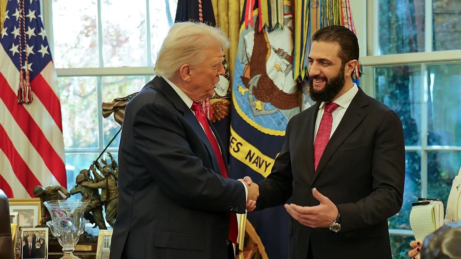 Two men shaking hands in front of flags
AI-generated content may be incorrect.