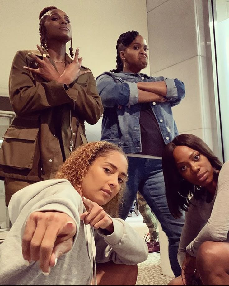 This may contain: four people standing in front of a mirror with their arms crossed and pointing at the camera This may contain: four people standing in front of a mirror with their arms crossed and pointing at the camera