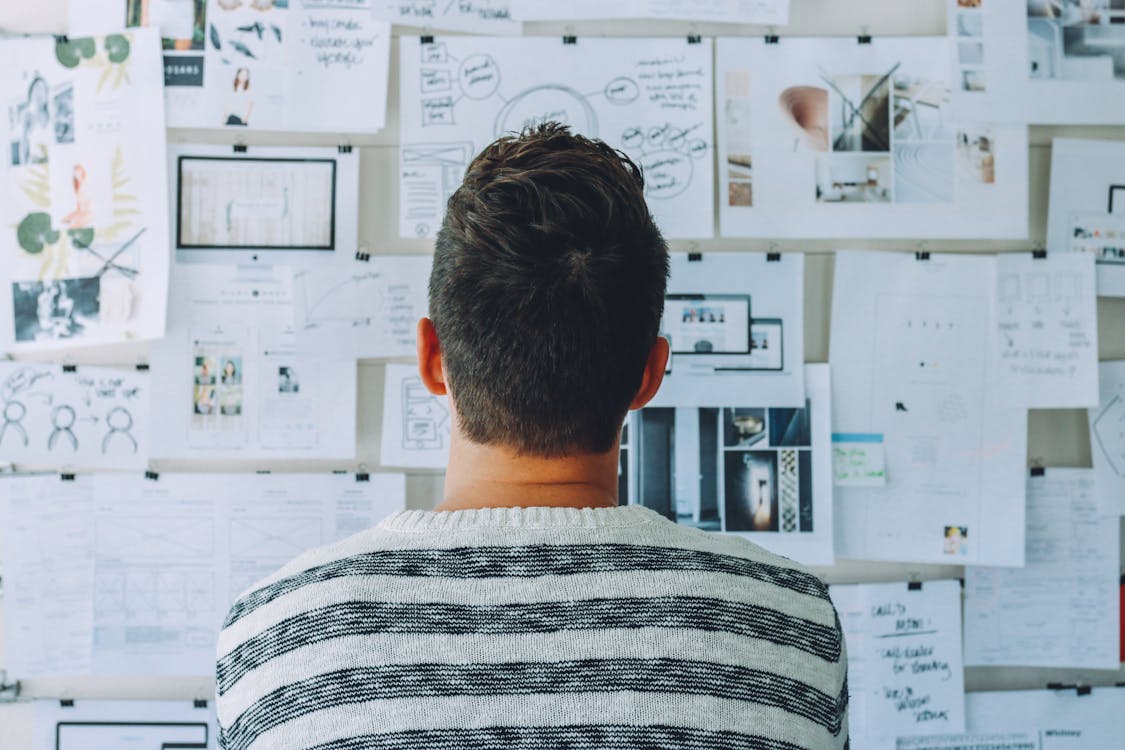 Free Man Wearing Black and White Stripe Shirt Looking at White Printer Papers on the Wall Stock Photo