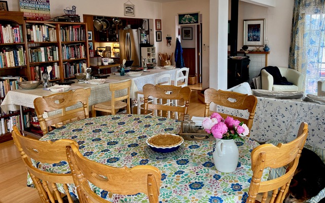 Large room with tables, lots of wooden chairs and bookcases in the background.