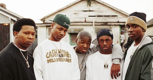 This may contain: four young men standing together in front of a house This may contain: four young men standing together in front of a house