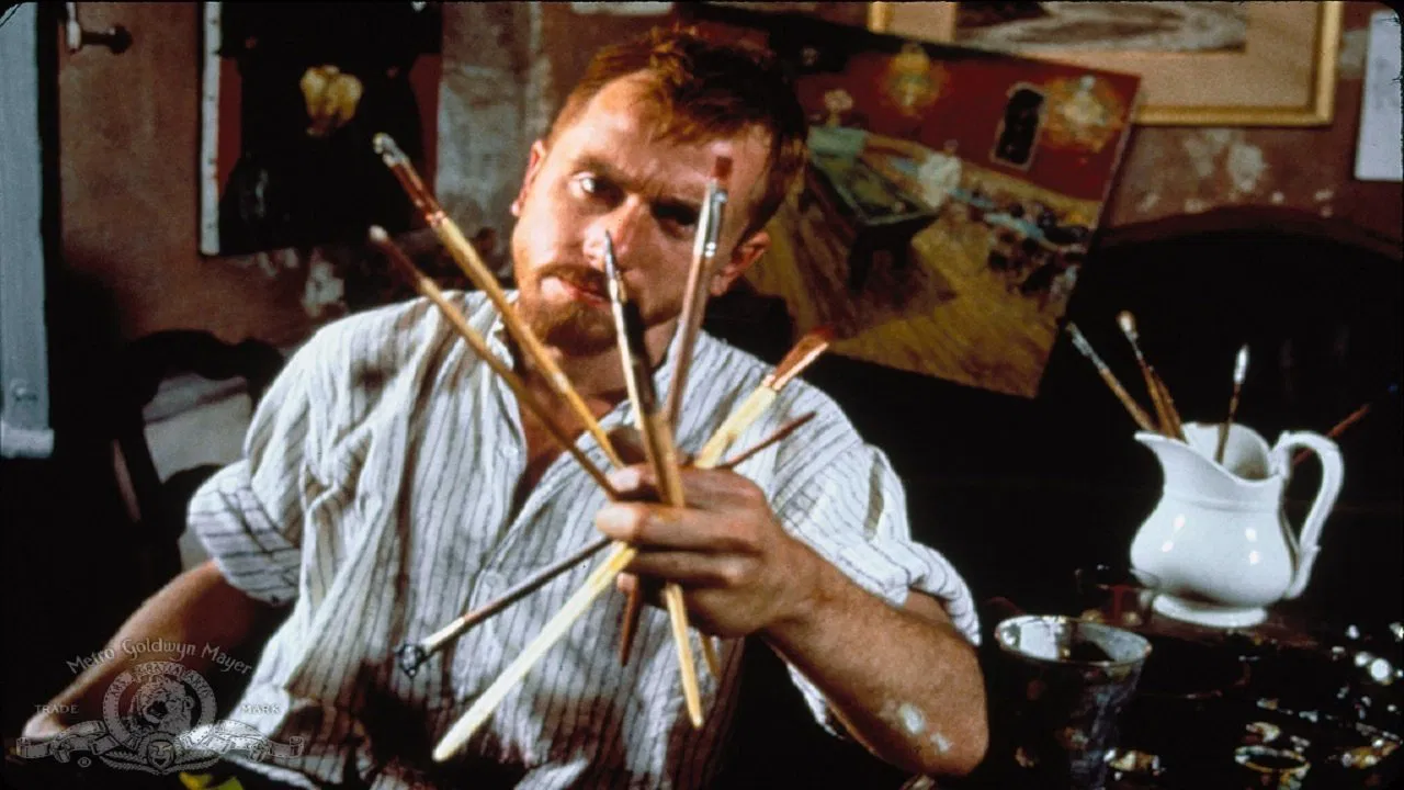 Kirk Douglas as Van Gogh holding paintbrushes in a studio scene