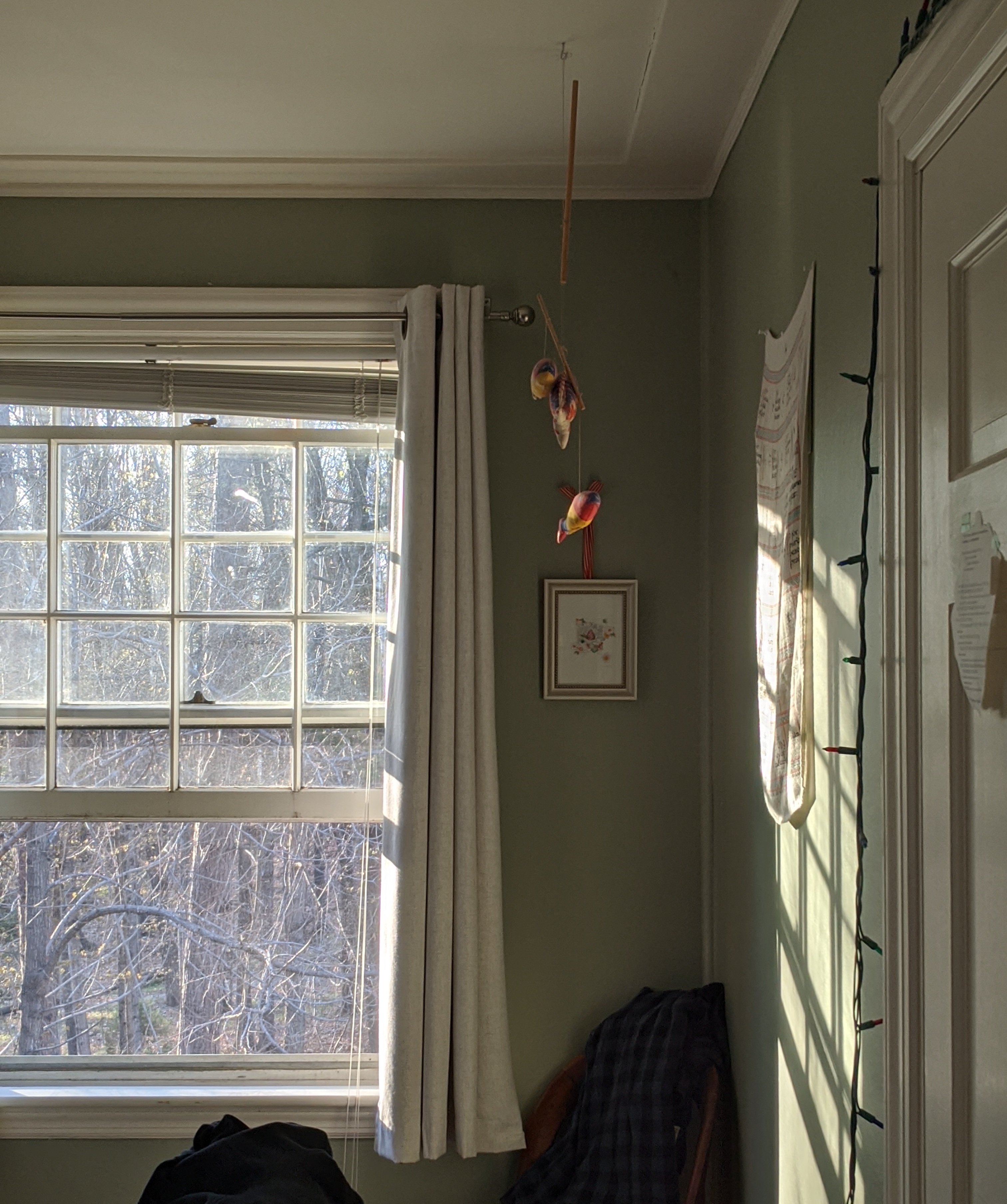 A wide-open window with a screen in a room with pale green walls