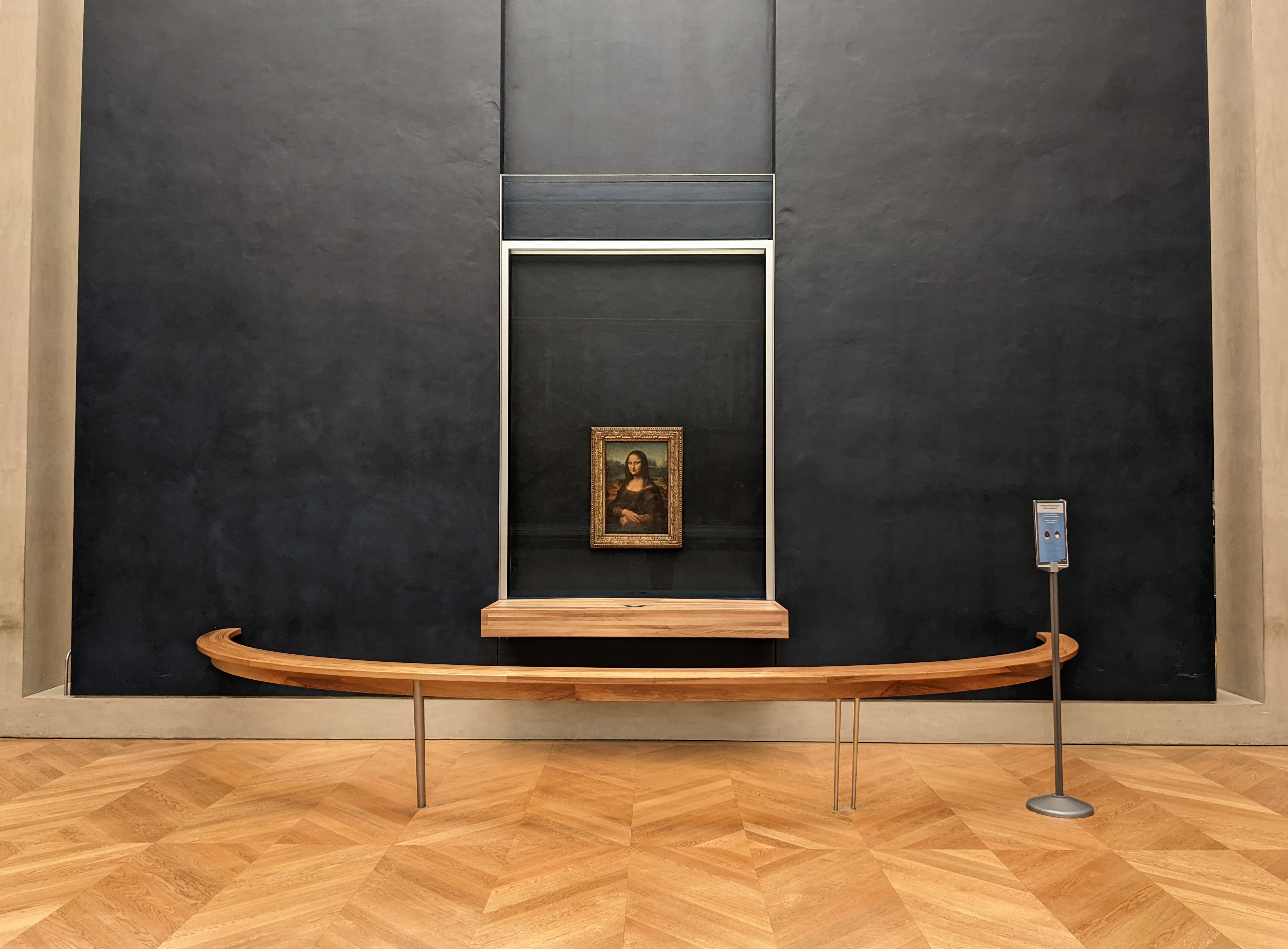 The Mona Lisa displayed behind a barrier in a Louvre gallery