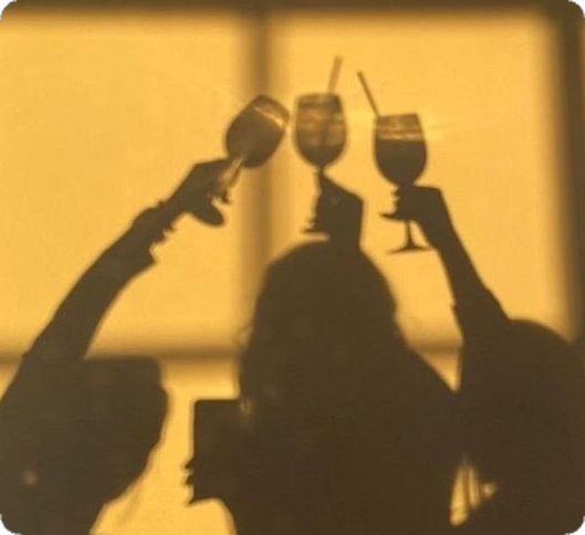 This may contain: two people holding up wine glasses in the air This may contain: two people holding up wine glasses in the air
