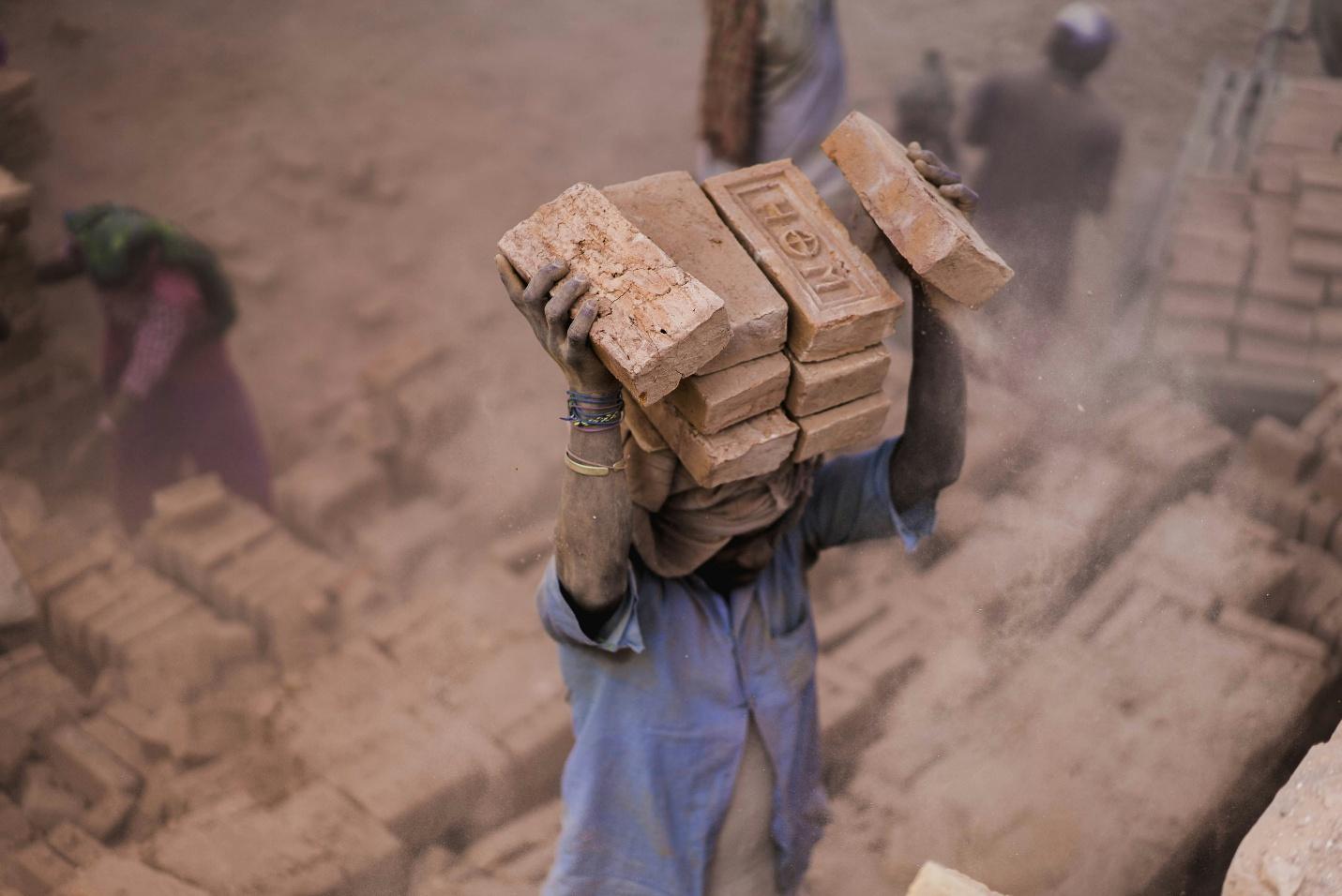 A person carrying bricks on his head
AI-generated content may be incorrect.