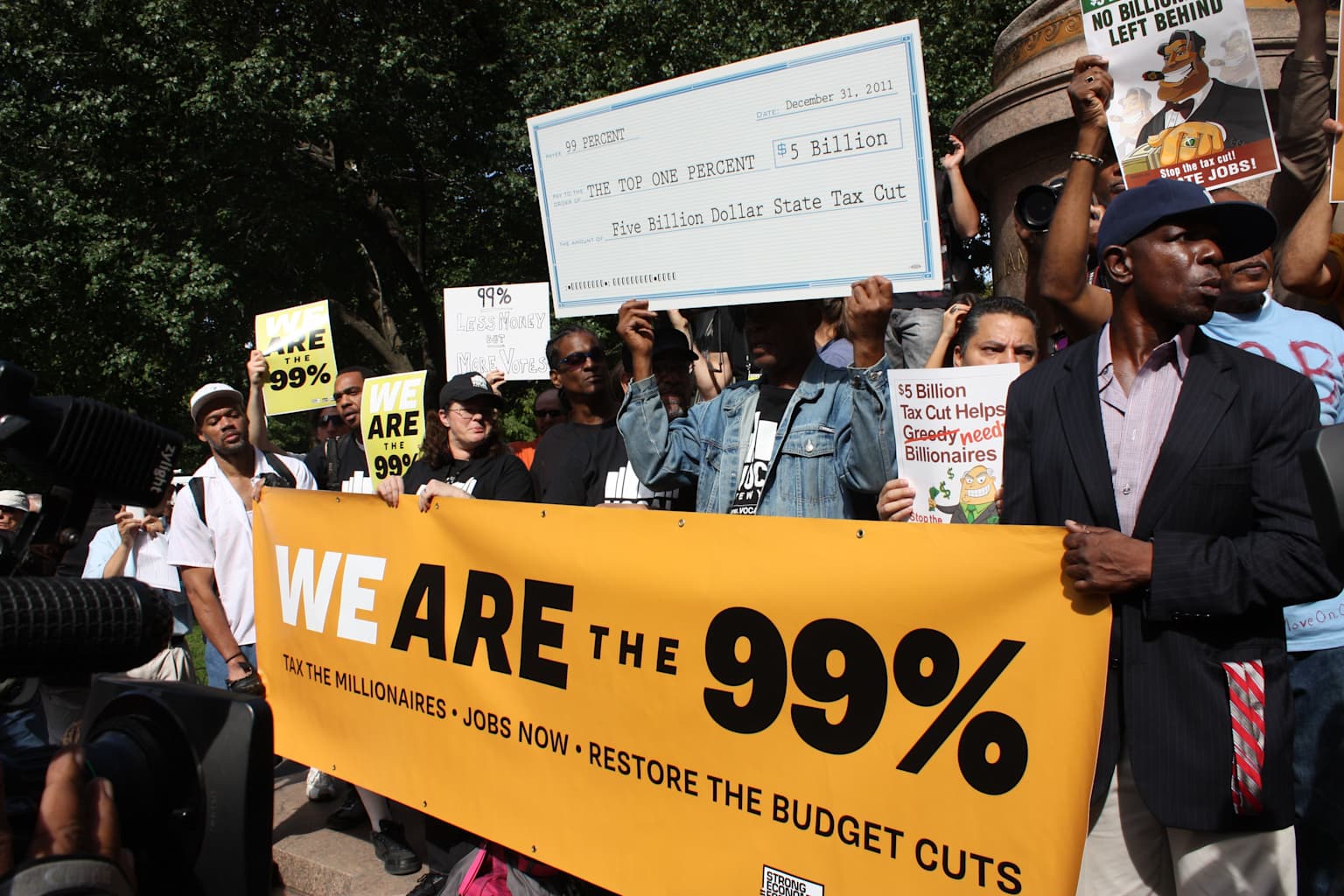 Occupy Wall Street protesters holding signs and banners advocating economic equality and opposing tax cuts for the wealthy