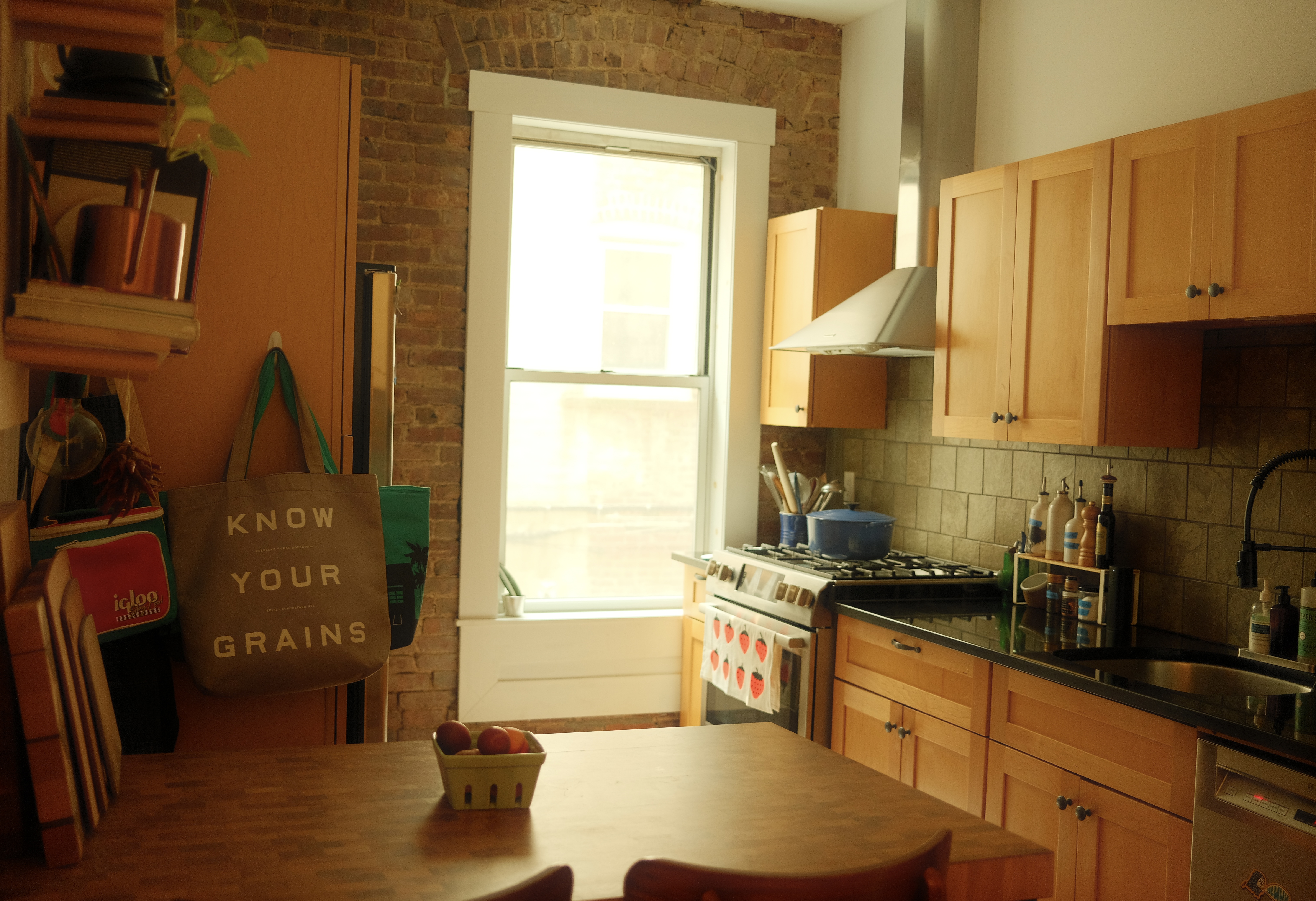 Kitchen with wooden table, bright window and wooden cupboard doors. Kitchen with wooden table, bright window and wooden cupboard doors.