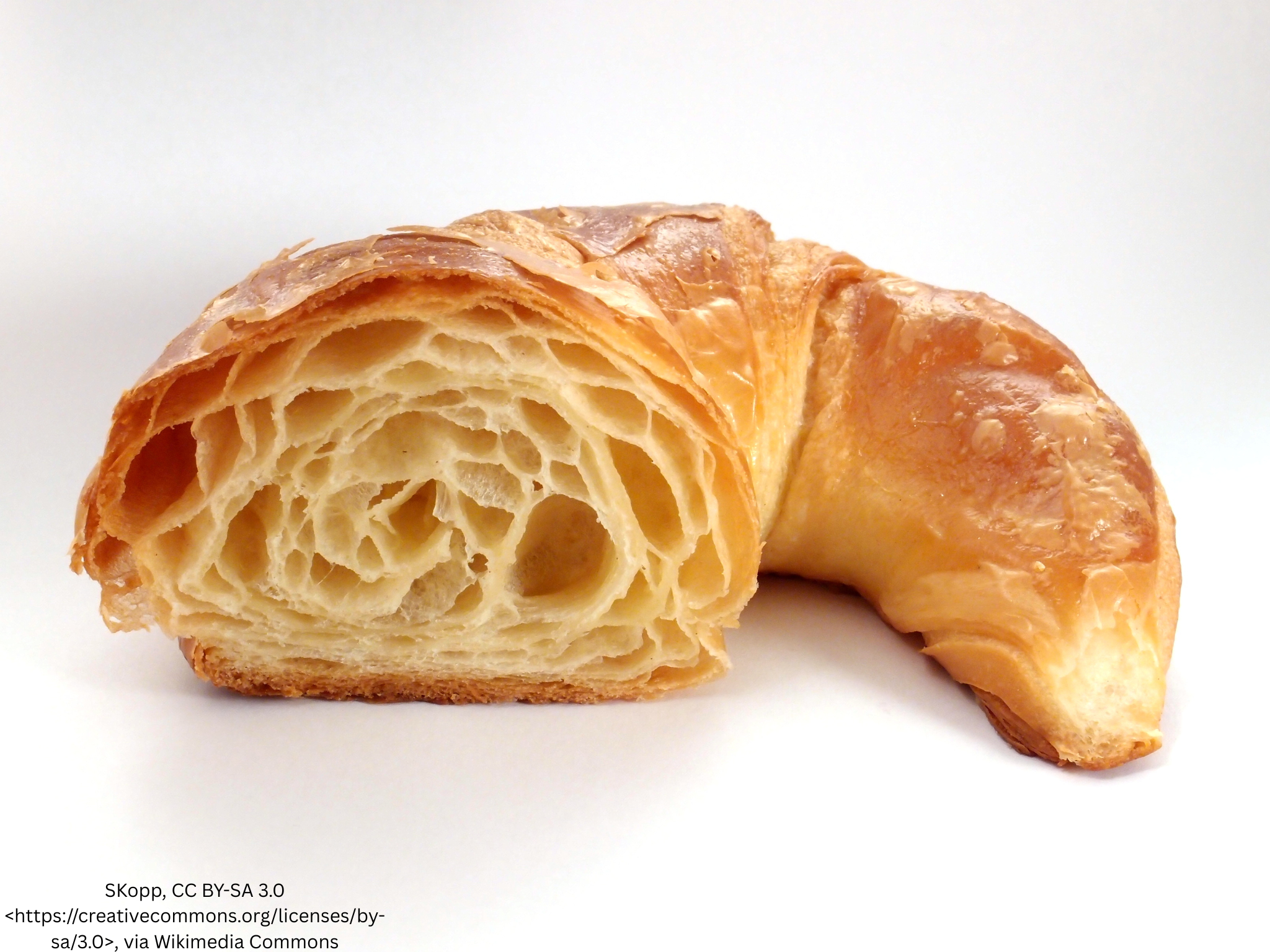 Croissant cut open to show its airy laminated layers