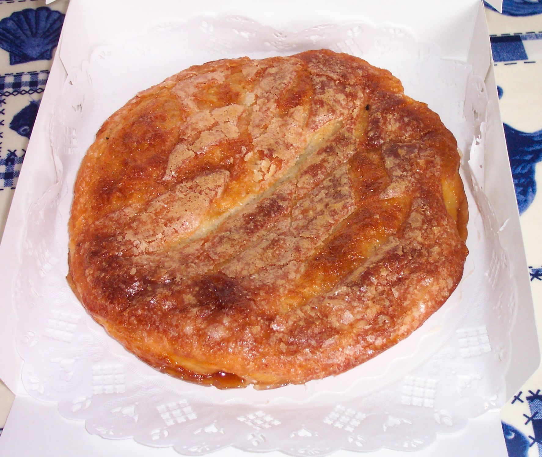 Round caramelized kouign-amann pastry on a white paper doily