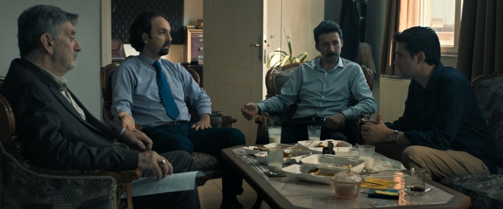 Filmden bir karede soldan sağa: Patron Ünal Silver, Avukat Erdem Şenocak, Büyük Oğul Bedir Bedir ve Küçük Oğul Mücahit Koçak. Şenocak’ı çok yakın zamanda Adsız Aşıklar’da da izledik, doğal, uğraşsız bir biçimde esprili oyunculuğu ile öne çıkıyor ve bu filmdeki avukat karakterini filmler arası bir geçişle Nacar’ın diğer filmi Tereddüt Çizgisi’nde de canlandırıyor.