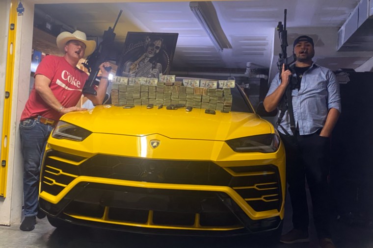 Former NC state trooper and DEA task force agent Freddie Wayne Huff and Rahain Deriggs, a sergeant in the Marine Corps, pose with military weapons stolen from Fort Bragg and money earned from trafficking cocaine with Los Zetas, a Mexican drug cartel.