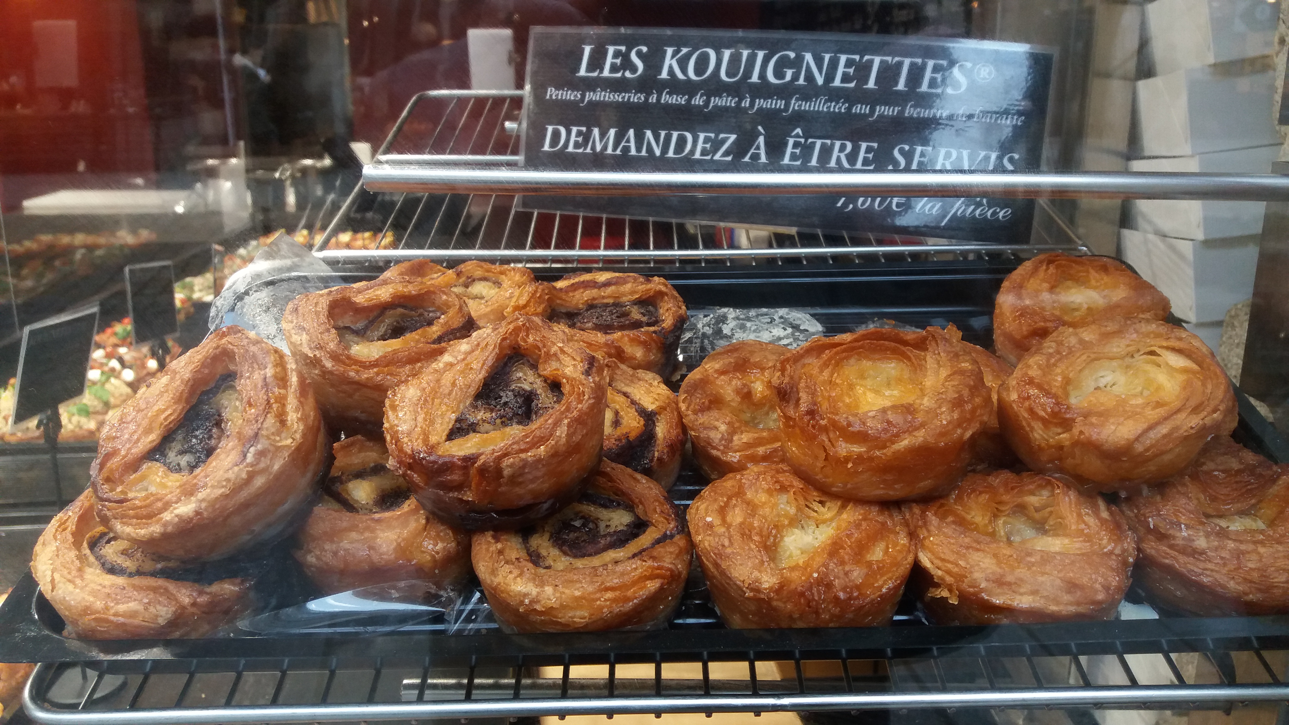 Tray of individual kouignettes displayed in a bakery window
