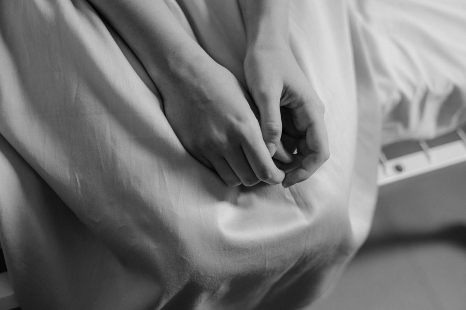 Light and airy close-up of two hands resting together on a white linen cloth, soft natural light from a nearby window, calm and still, no faces visible