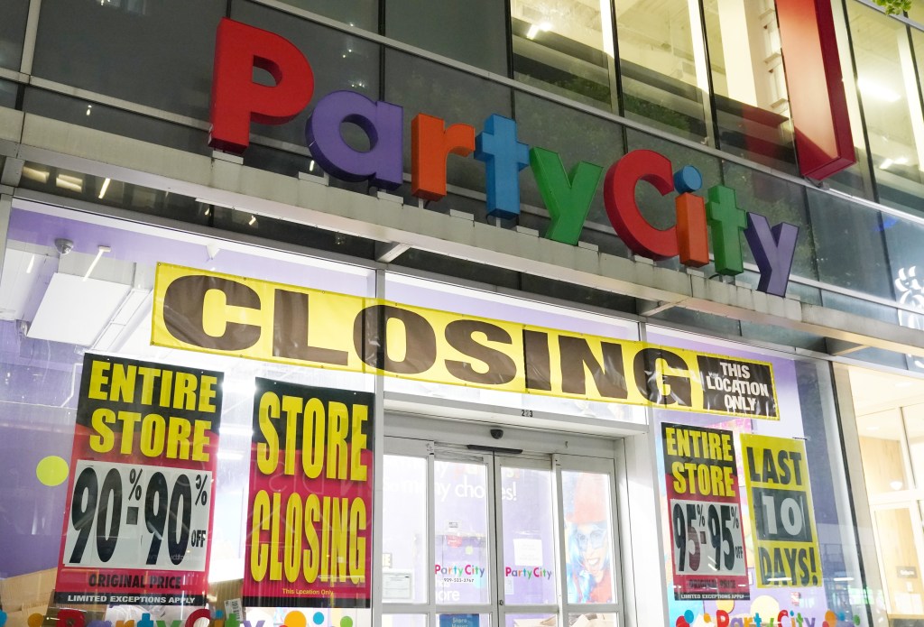 The exterior of a Party City store with "CLOSING" banners and sale signs, advertising discounts of 90-95% off.