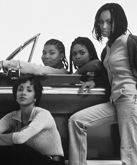 This may contain: four young women sitting on the back of a car in front of a man standing next to them This may contain: four young women sitting on the back of a car in front of a man standing next to them