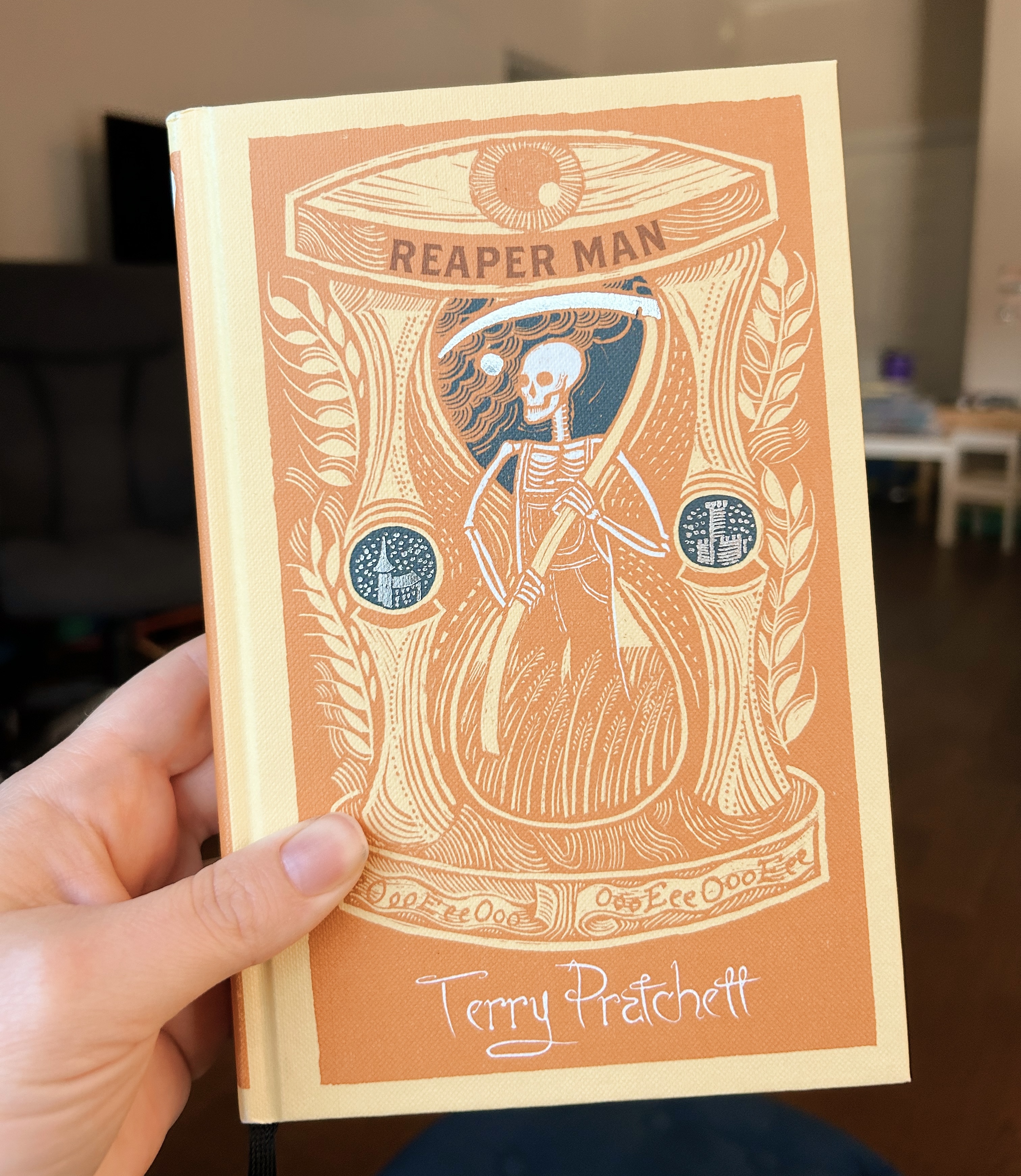 Hardcover Unseen University edition of Reaper Man by Terry Pratchett featuring a skeleton in overalls holding a scythe within an hourglass.