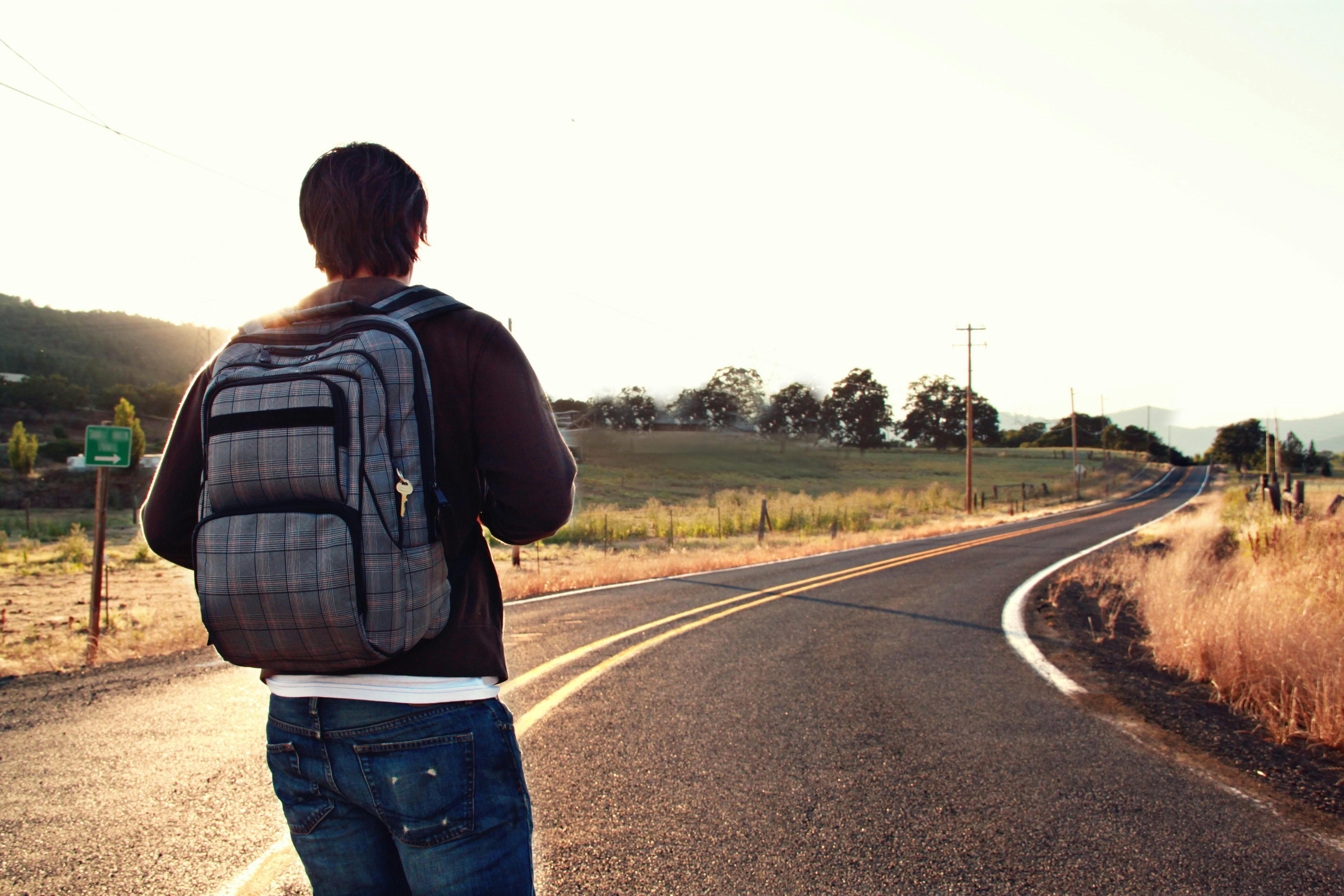 Man with a backpack embarking down a road