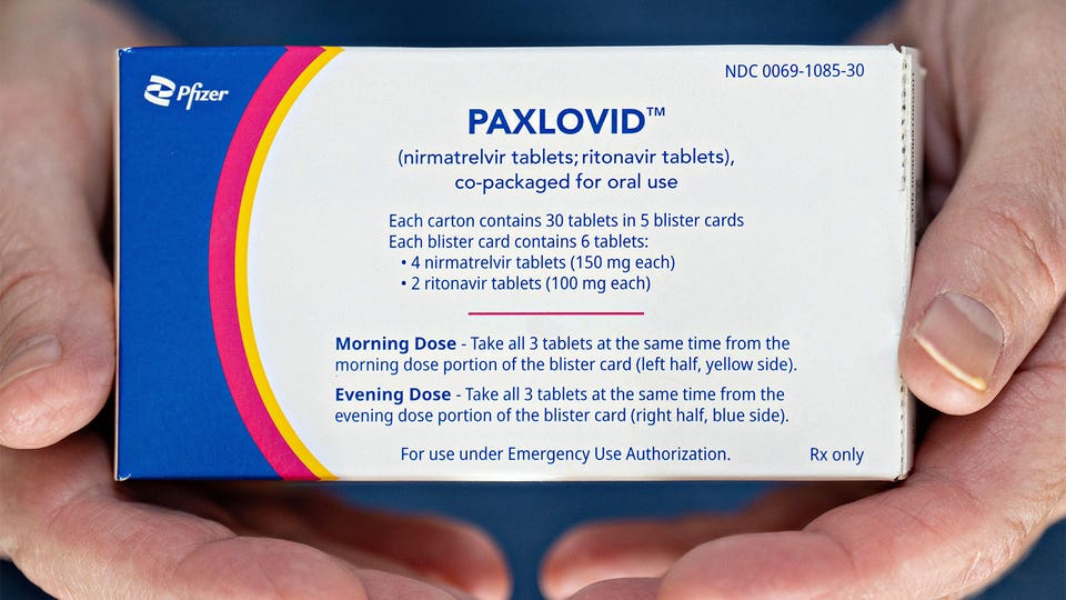  A close up photo of a man holding a box of Paxlovid.