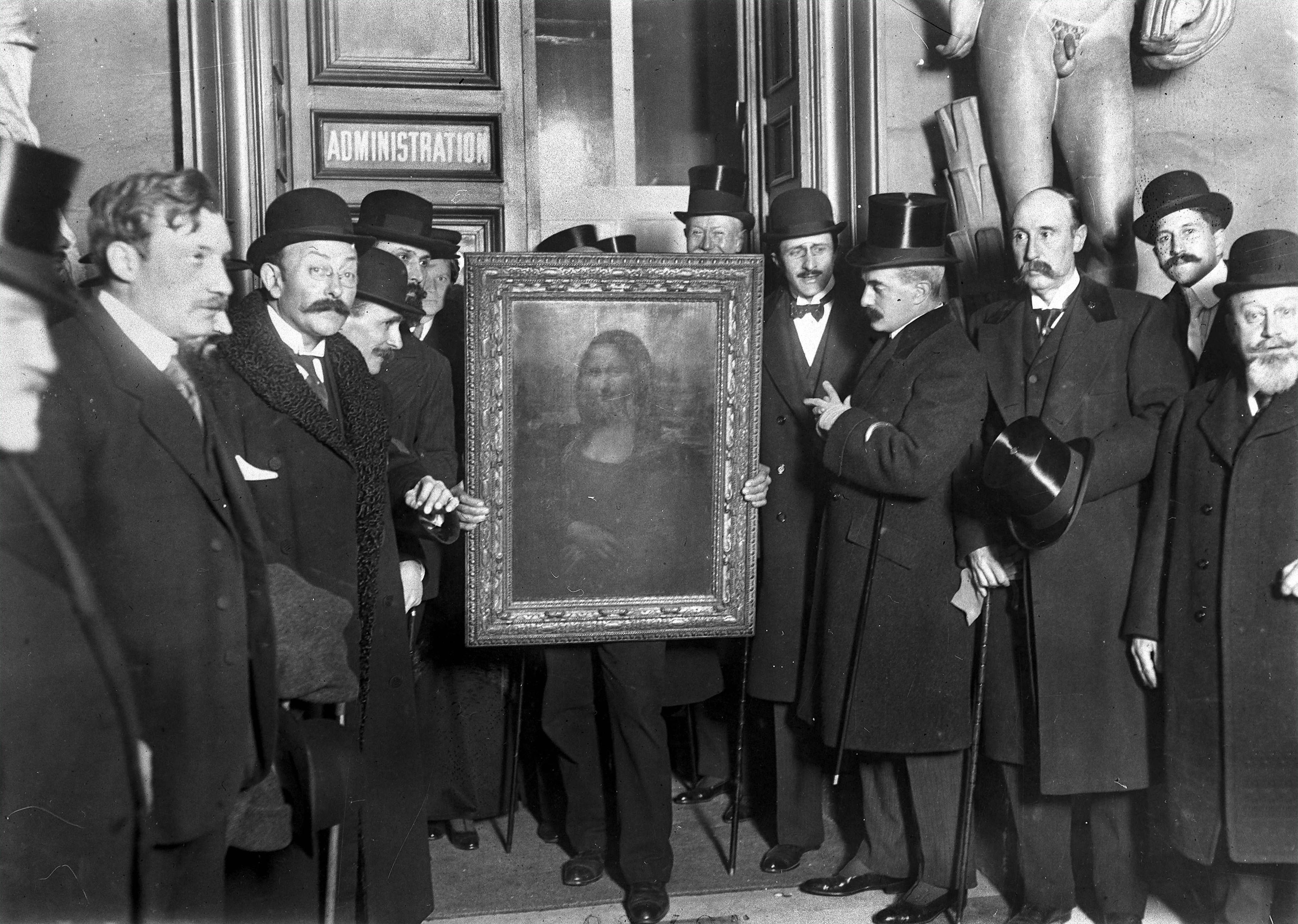 Historic black-and-white photograph of men gathered around the framed Mona Lisa