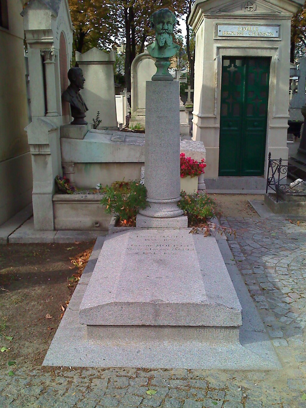 Stone grave marker with a bronze bust in a cemetery