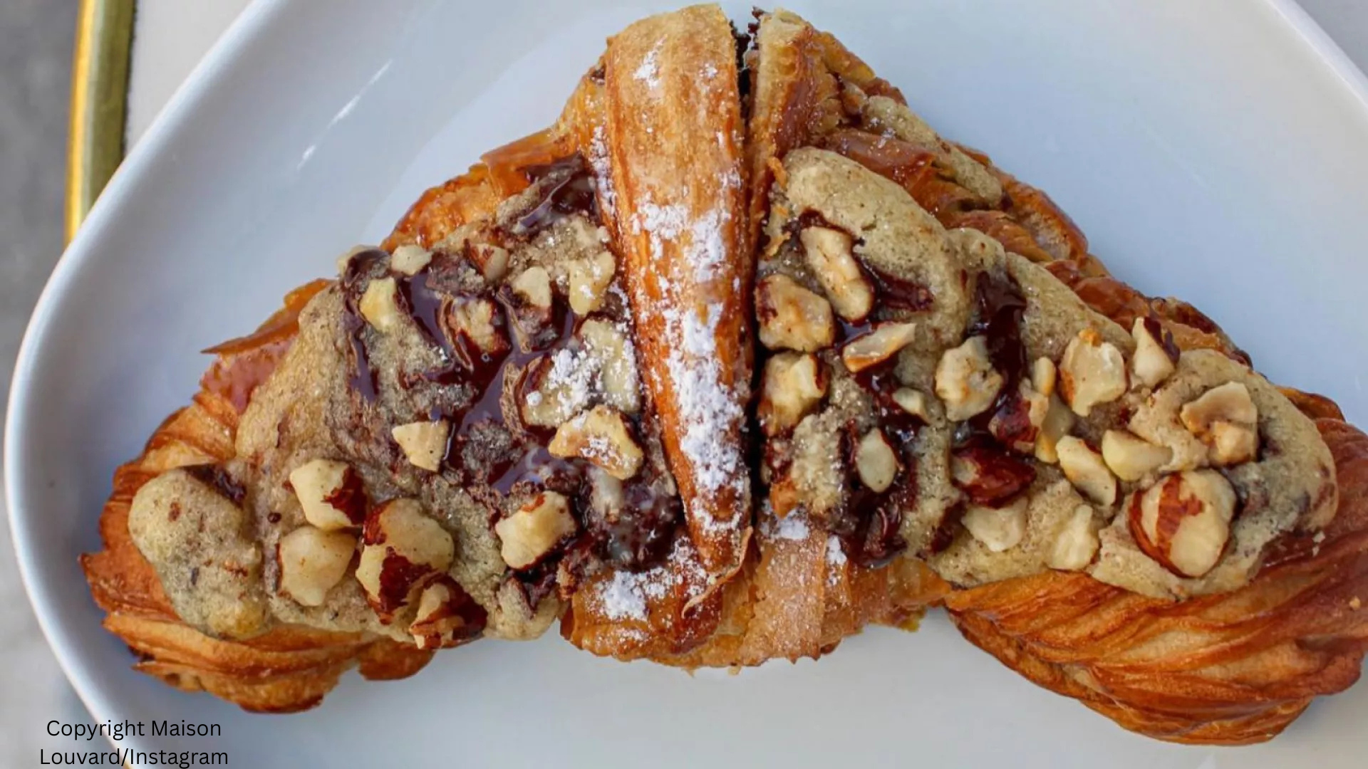 Nut-topped chocolate-filled croissant on a white plate