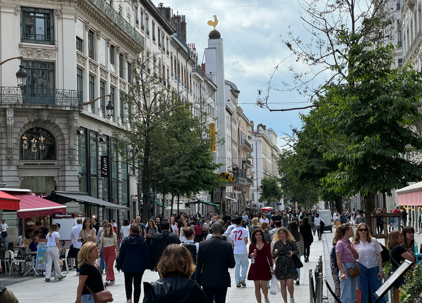 A group of people walking on a sidewalk

Description automatically generated