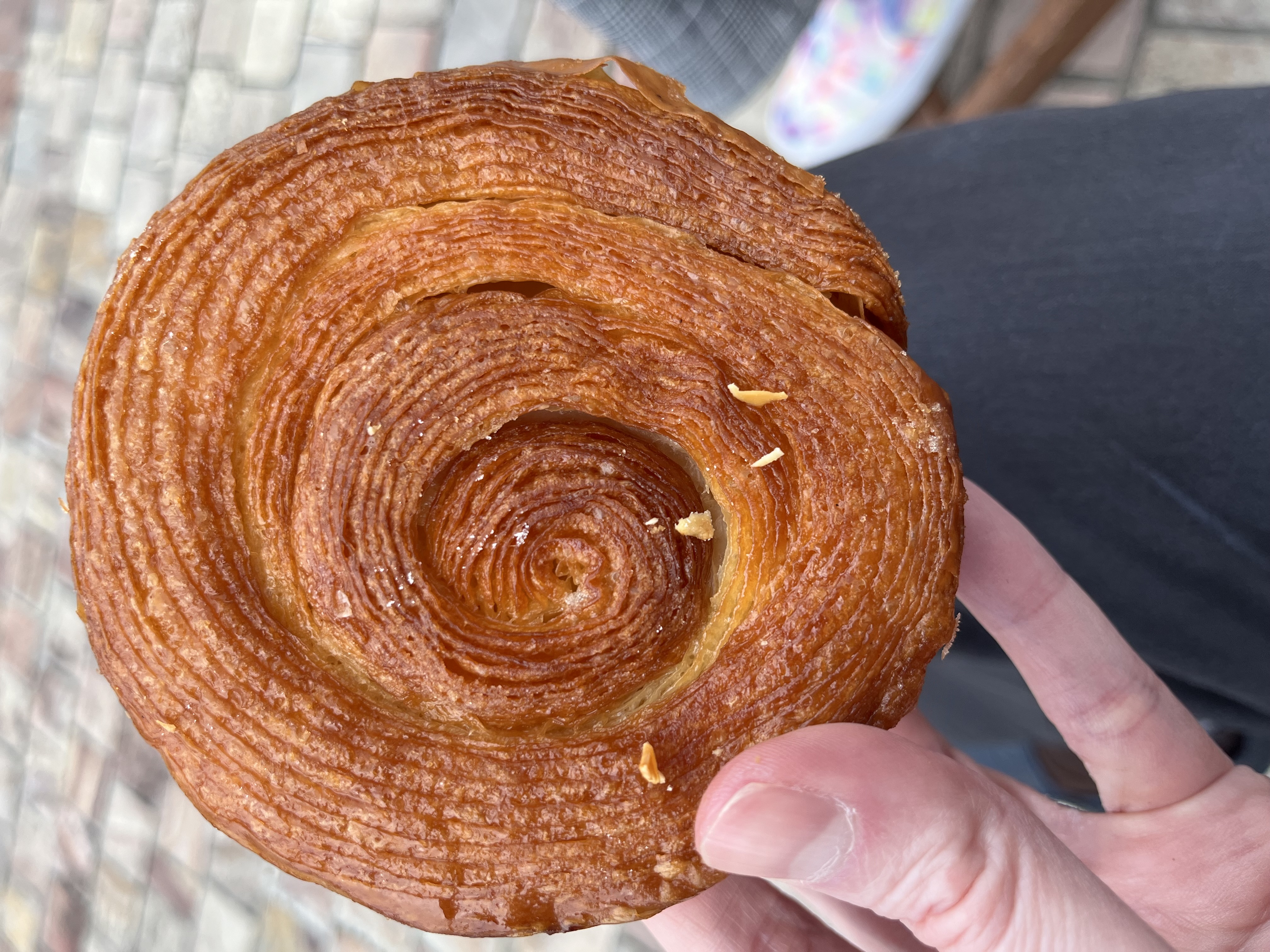 Spiral-layered kouign-amann pastry held in one hand