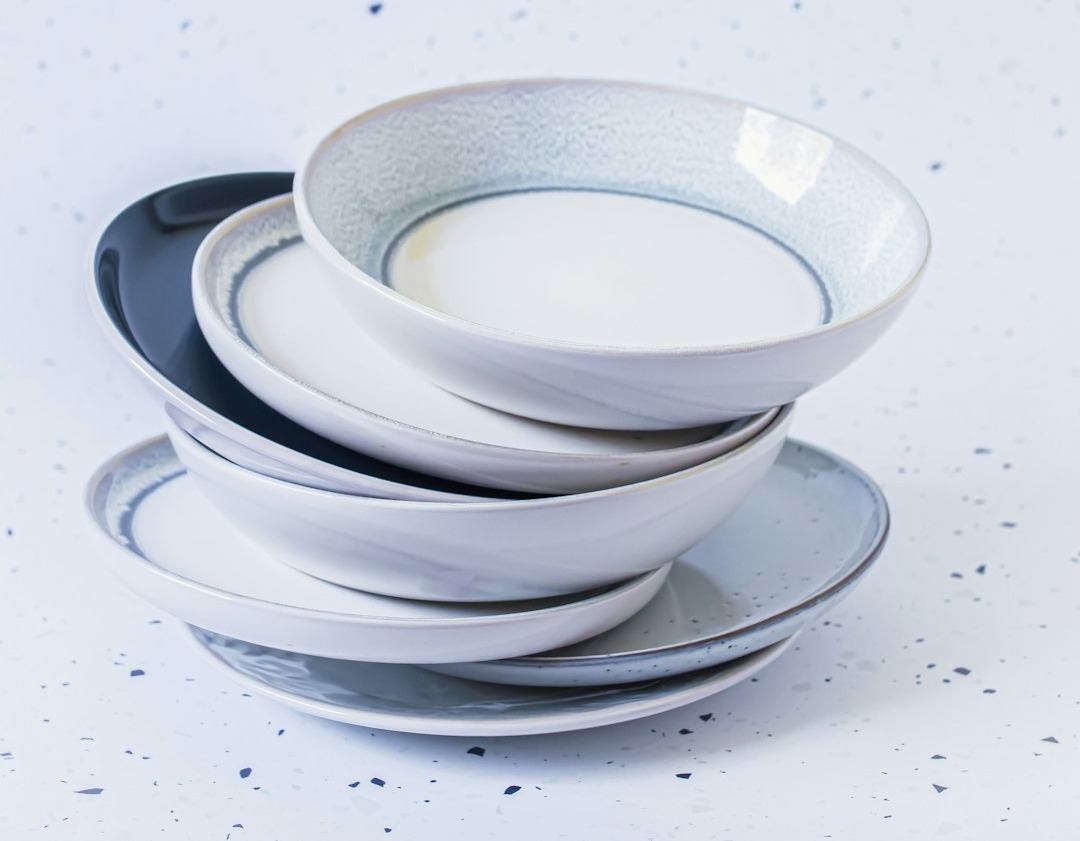 a stack of white and black plates on a white table