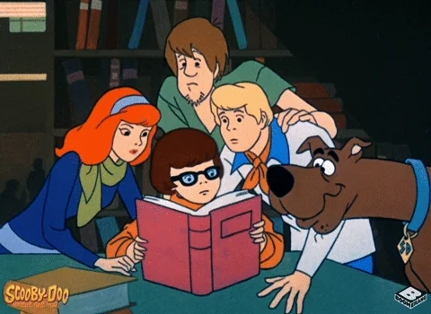 a GIF from an animated Scooby Doo movie, in which Daphne, Fred, Velma, Shaggy, and Scooby look from a book to the viewer
