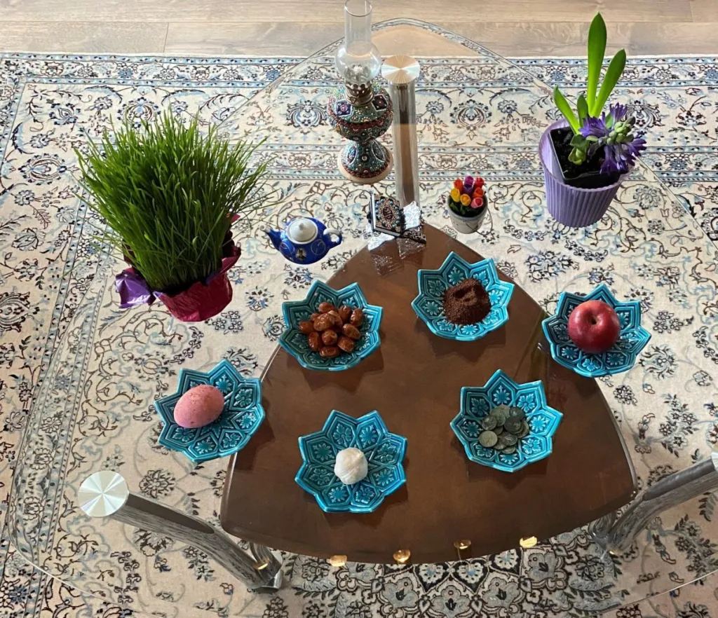 Nowruz haft-seen table with sprouts, hyacinths, fruit, and symbolic dishes