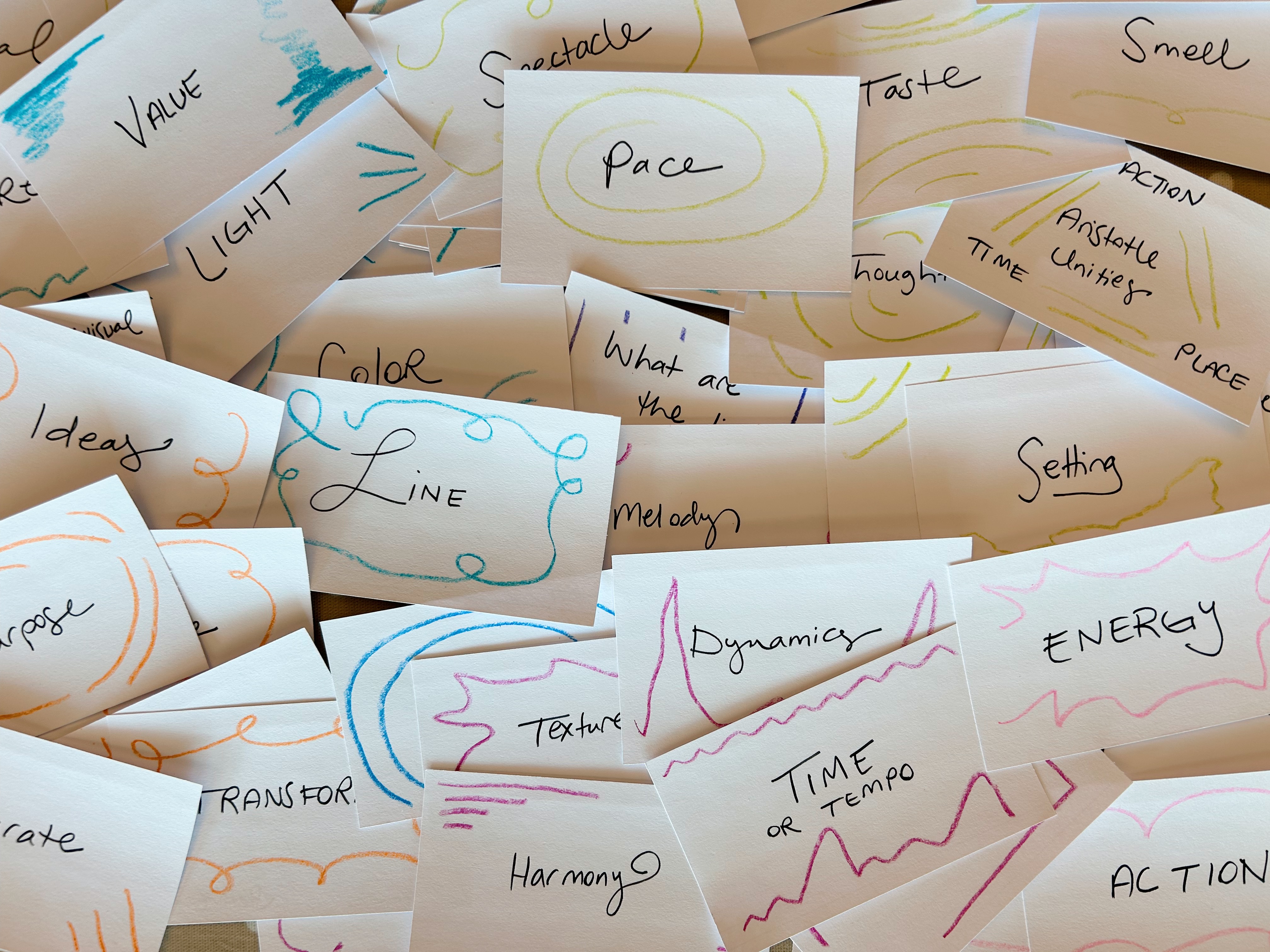 Pile of index cards with words like light, pace, line, dynamics, tempo, energy, action, harmony. Crayon doodles surround words.