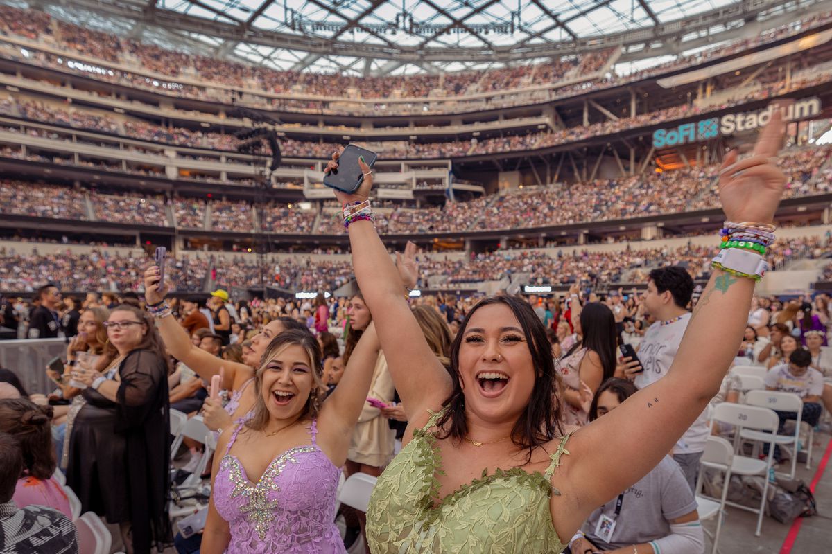 Fans with their arms raised in a crowded stadium