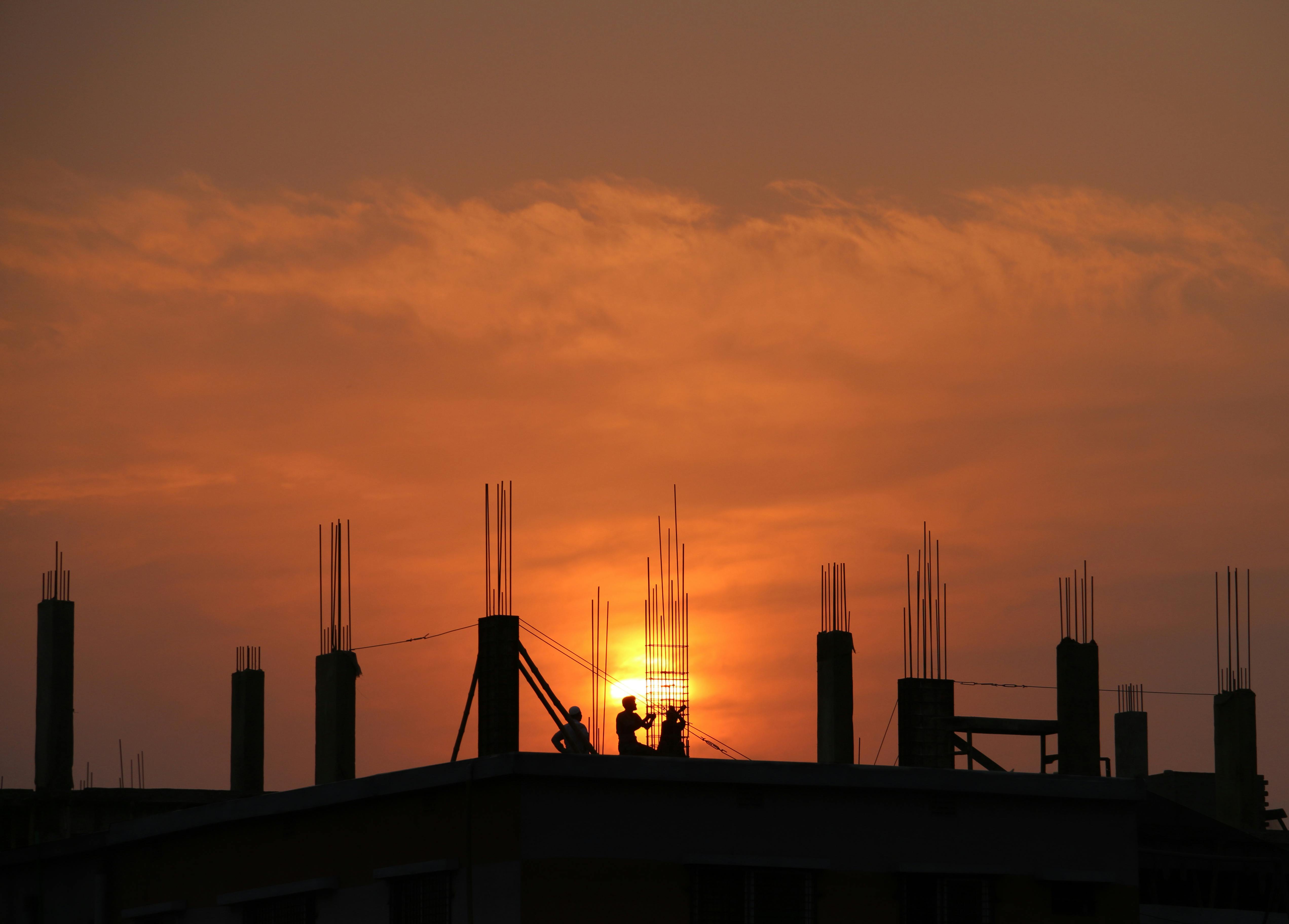 Silhouette of a building under construction in front of a sunset
