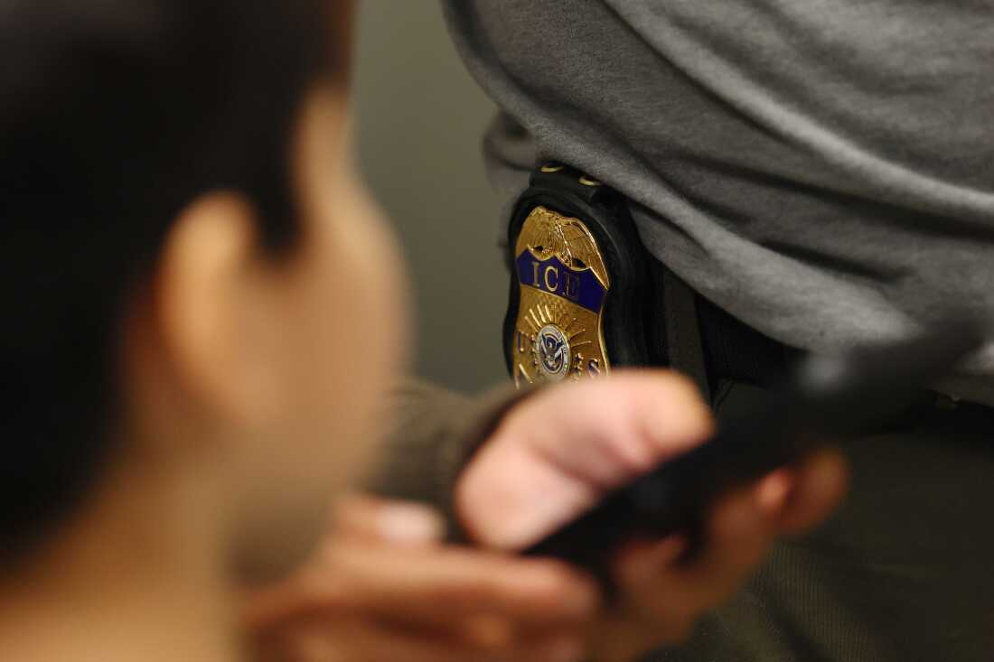 NEW YORK, NEW YORK - JULY 23: A child looks at the badge of an Immigration and Customs Enforcement (ICE) agent as his family is helped in the halls of immigration court at the Jacob K. Javitz Federal Building on July 23, 2025 in New York City. NYC Comptroller Brad Lander and NYC Public Advocate Jumaane Williams visited immigration court to witness active proceedings as detention of immigrants attending court hearings continue. The lawmakers also attempted to gain access to inspect the 10th floor of 26 Federal Plaza after a video was leaked earlier this week where the ICE agency has been holding detainees since ICE stepped up arrests this summer. Immigrants who have been detained have complained about overcrowded and unsanitary conditions inside the holding cells. (Photo by Michael M. Santiago/Getty Images)