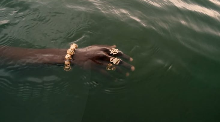This may contain: a man swimming in the water with two gold bracelets on his hand This may contain: a man swimming in the water with two gold bracelets on his hand